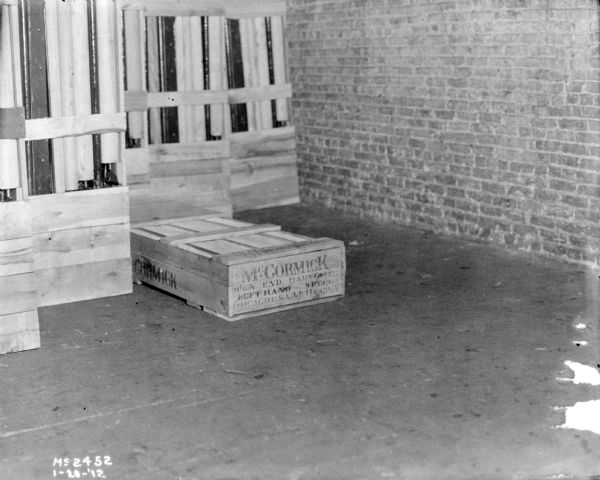 A crate on the floor indoors at McCormick Works. Other crates are stacked upright on the left. Printed on the crate: "McCormick, Open End, Left Hand."