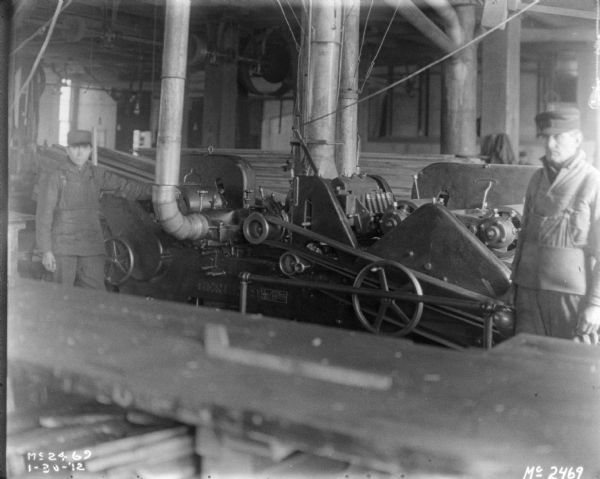 Large manufacturing machine indoors at McCormick Works. Two men are standing near the machine.