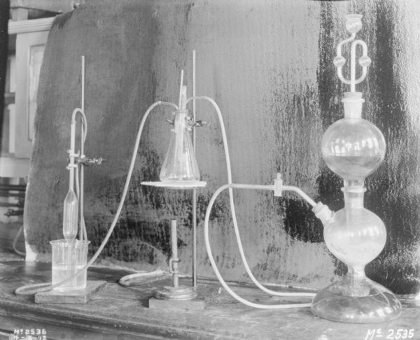 Laboratory experiment set up in a factory building. There is a backdrop behind the table which is holding glass vessels and tubes.