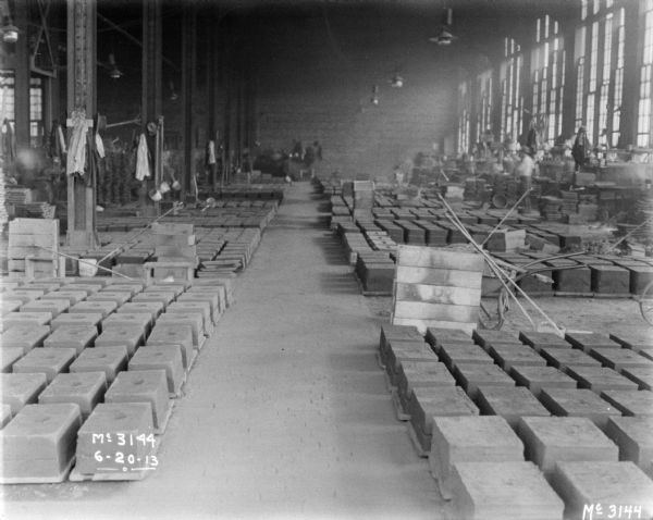 Interior view of the forging area in the factory. Men are working in the background.