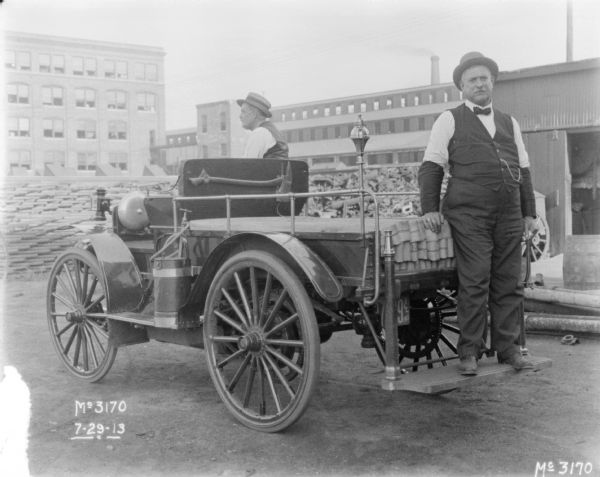 View of two men posing with an International Highwheeler fire truck outdoors at McCormick Works.