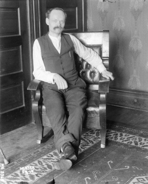 Man posing sitting in a chair in a living room.