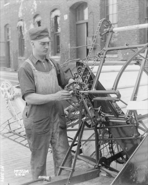 Man demonstrating assembly of parts on a Binder outdoors in the factory yard.