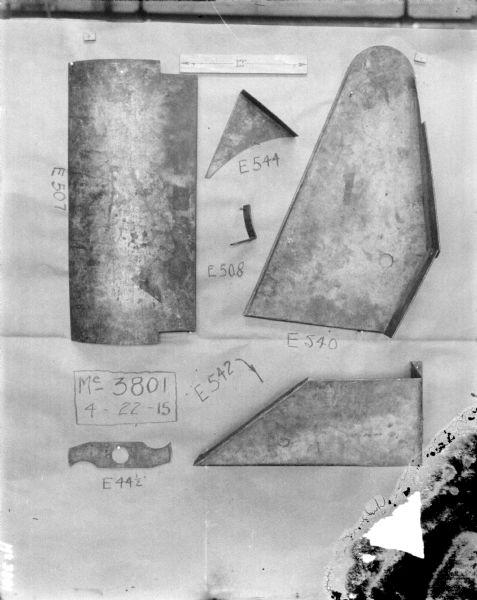 Parts are displayed on a board. At the top is a piece of paper that has a double-sided arrow with 12" written in the center. Part numbers are written below.
