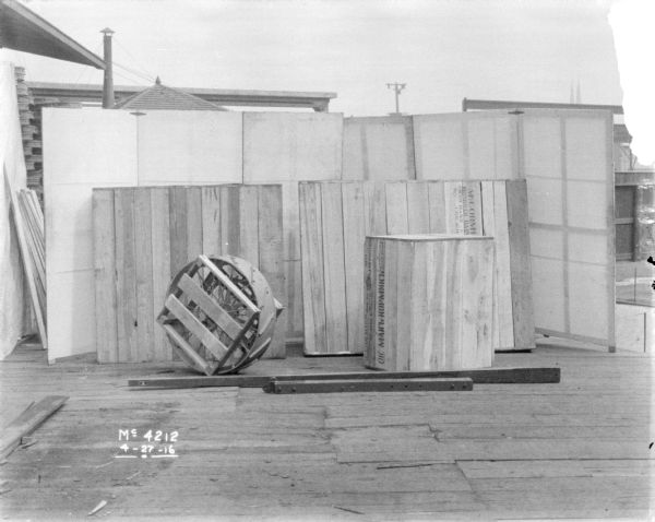Harvester Thresher packaged for shipping outdoors in factory yard. The crates are labeled in Russian. A backdrop is behind the crates.