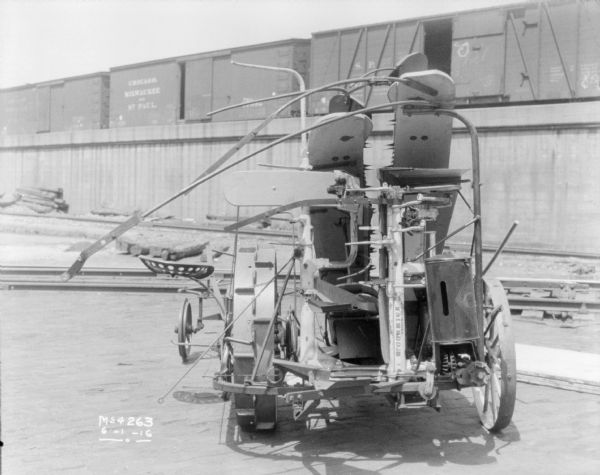 Corn Binder outdoors in the factory yard. In the background are railroad cars on an elevated platform.