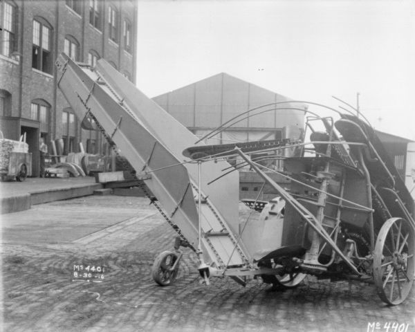 Corn Binder outdoors in factory yard. A loading dock and brick building is in the background on the left.