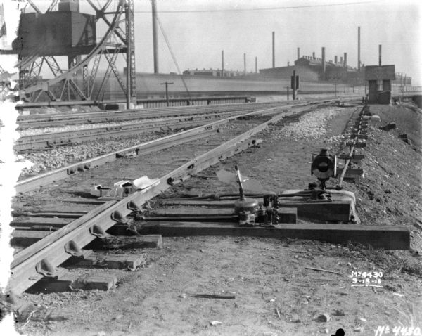 View of railroad yard, with plant in the distance. Detail of switches in foreground.