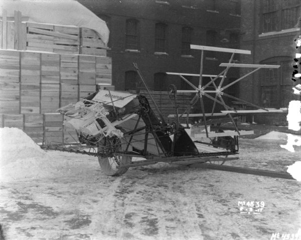 Binder on transport truck outdoors in factory yard. Crates, probably for shipping, are stacked near a brick building in the background.