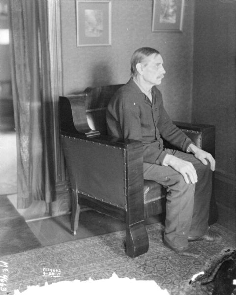 Portrait of a young man sitting in a chair facing the right. The man is most likely a factory worker from International Harvester's McCormick Works in Chicago.