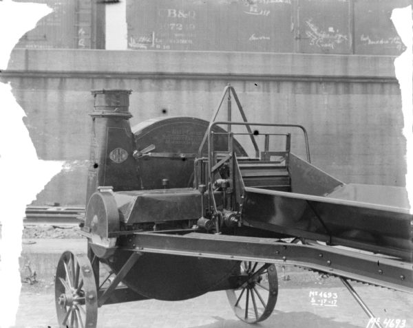 Ensilage Cutter in factory yard. In the background are railroad cars on an elevated platform.