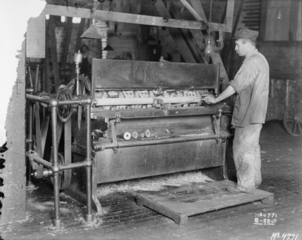 Factory worker placing a piece of wood into a machine at International Harvester's McCormick Works.