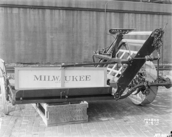 Milwaukee Binder set-up on a crate outdoors in factory yard. In the background railroad cars are on an elevated platform.