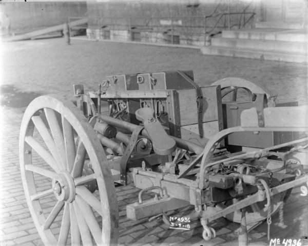 Details of loaded guns and ammunition on a Gun Cart outdoors in factory yard, with a brick building in the background.