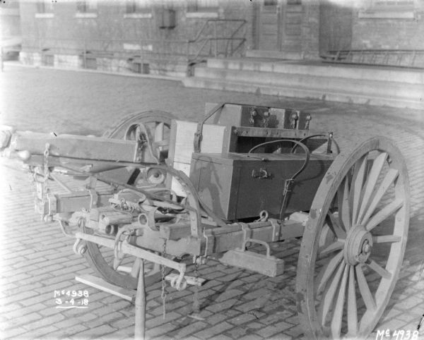Details of loaded guns and ammunition on a Gun Cart outdoors in factory yard, with a brick building in the background.
