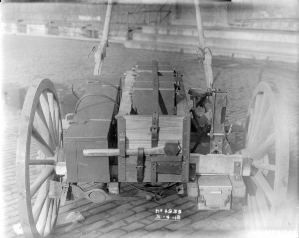 Details of loaded guns and ammunition on a Gun Cart outdoors in factory yard, with a brick building in the background.