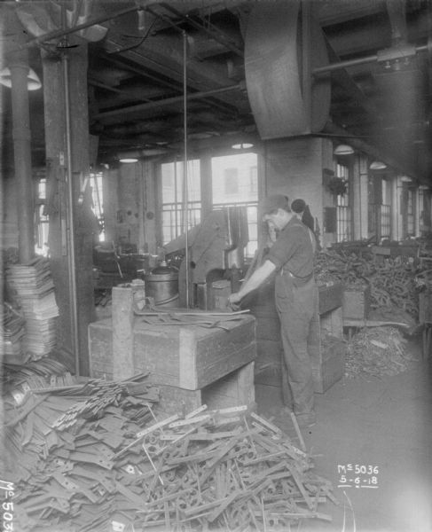Men bending metal parts on factory floor.