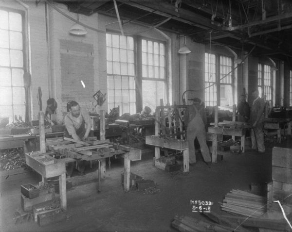 Men are bending metal parts on factory floor.