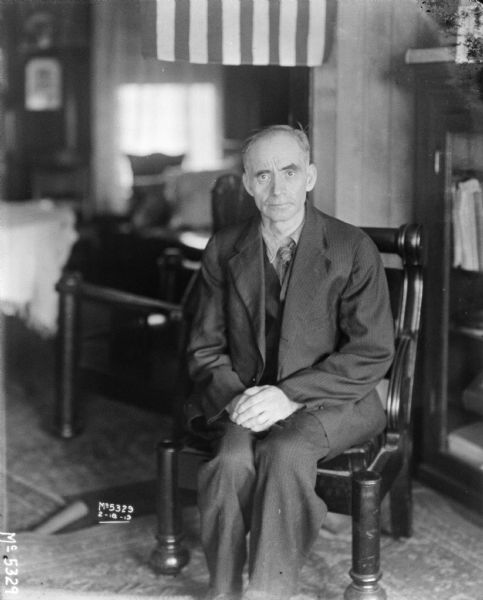 Portrait of a man wearing a suit sitting in a chair.