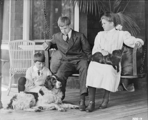 Group portrait on porch of the three children of Cyrus Hall McCormick, Jr. (1859-1936), and his wife, Harriet Bradley Hammond (1862-1921). Pictured, left to right, with two pet dogs are: Gordon (1894-?) kneeling, Cyrus III (1890-1970), and Elizabeth (1892-1905) sitting in a porch swing.