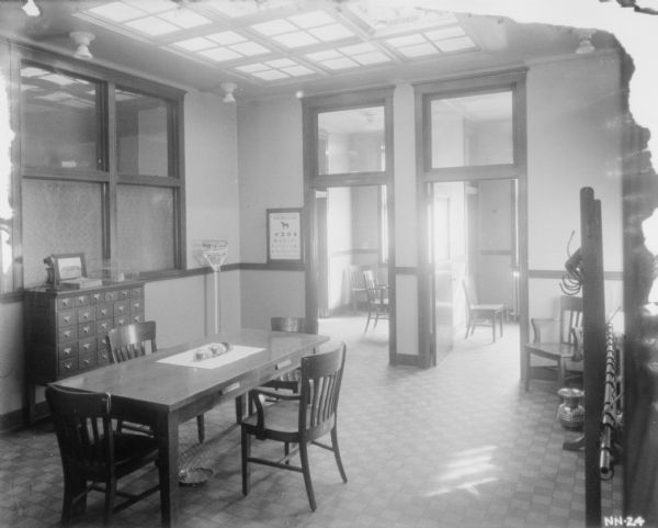 Interior view of a doctor's office. There is a skylight in the ceiling above a table and chairs. Two rooms with doors are in the background.