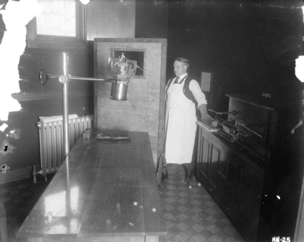 Interior view of a laboratory. A man is standing on the right near a large table.
