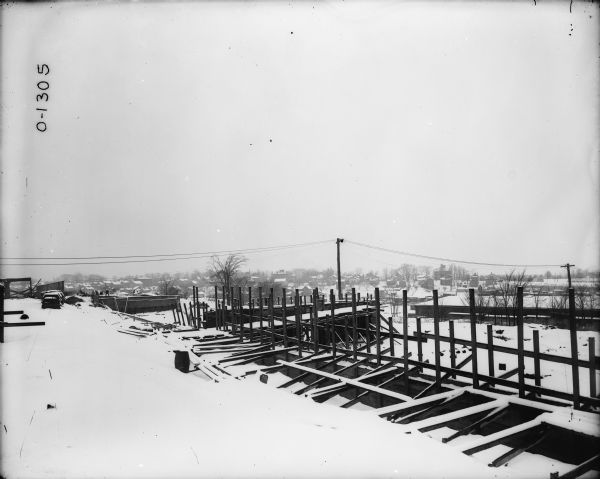 Elevated view of plant under construction. Snow is on the ground, and houses are in the distance.