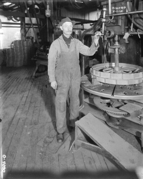 Employee posing at wheel manufacturing machine.