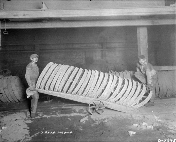 Men moving a stack of wheels on a cart to the outside of a warehouse.
