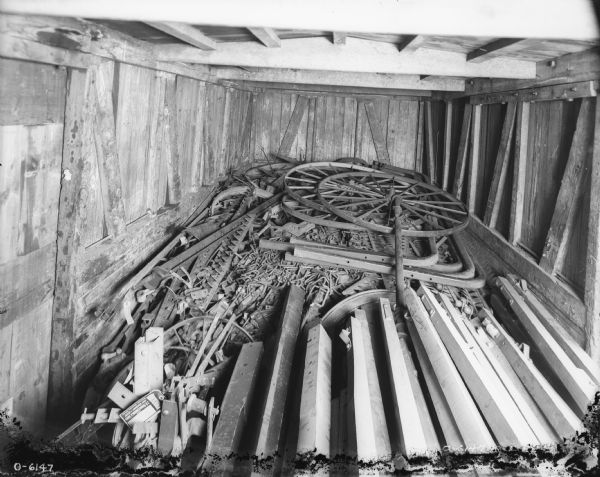 Parts of various kinds are stacked in a wooden storage area, perhaps a railroad car.