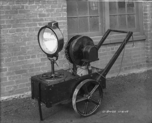 Power generator on a cart outdoors near a brick wall.