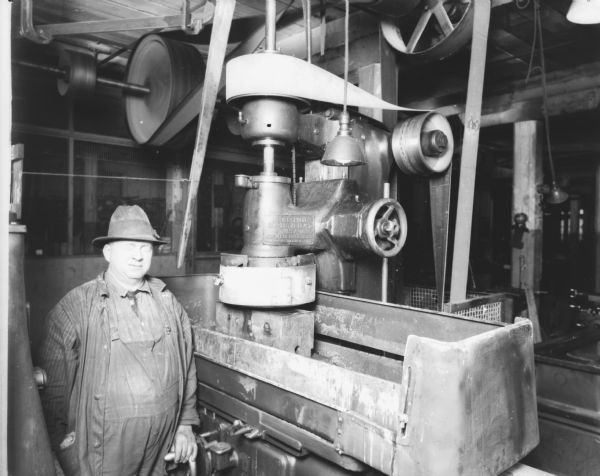 View of a man standing in the boiler/turbine room. A sign on the machine reads: "Oil all spindle bearings at least 4 times a day."