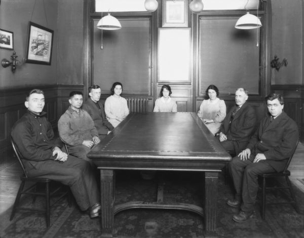 Employees(?) posing around a large table in a boardroom.
