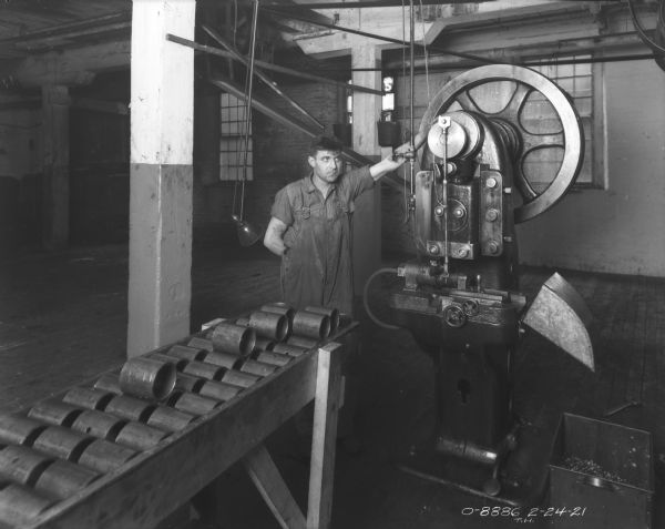 Man posing with manufacturing machine in plant.