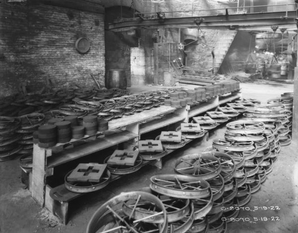 Wheels stacked in a storage area. Men (blurred by movement) are working in the background.