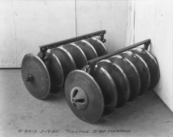 Close-up of a tractor Disk Harrow part set up on a floor in front of a backdrop.
