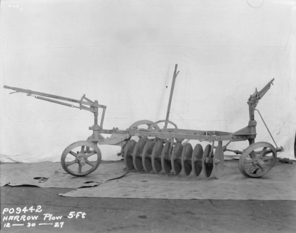 5 Foot Harrow Plow set up on paper on factory floor. A backdrop is hanging behind the plow.