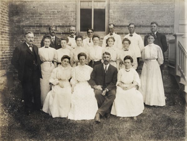 Outdoor group portrait of the Winnebago County Asylum administrative and nursing staff. Included in the portrait are the Superintendent, E.E. Manuel, his wife and the Matron, Olphene (Stromme) Manuel (both front and center), and their daughter (third from the left, middle row), Bessie Leone (Manuel) Briggs.