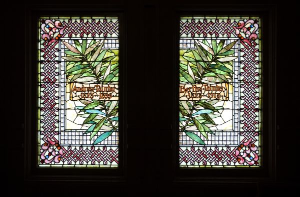 Close-up of stained glass window in the Mabel Tainter Memorial Theater commemorating Andrew and Bertha Tainter and produced by Tiffany Glass Company.
