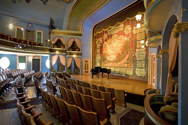 View of Stoughton Opera House stage, advertising curtain and boxes from front of auditorium.