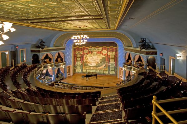View of Stoughton Opera House stage, advertising curtain and auditorium from balcony.