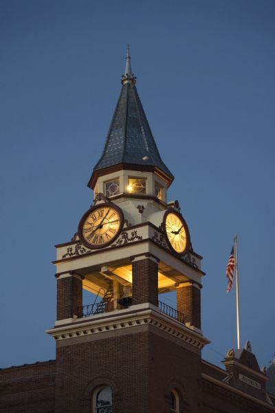 Exterior view of Independence City Hall and Opera House clock tower illuminated at dusk, including flagpole.
