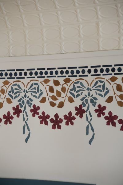 Close-up of recreated stencil work on auditorium walls of Thrasher Opera House, featuring bows and flowers.