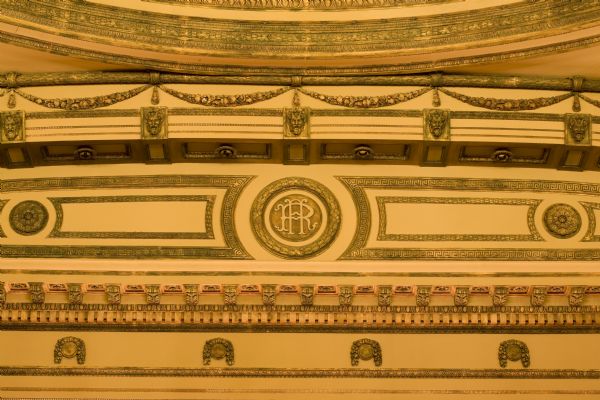 Close-up of decorative carving and plasterwork above the stage in the Al. Ringling Theatre including a cartouche with the initials AR, flower garlands and the Greek God Pan.