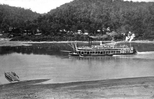 Elevated view of a steamboat on the Ohio River near Georgetown, with housing visible on the opposite shore and a small dock in the foreground.