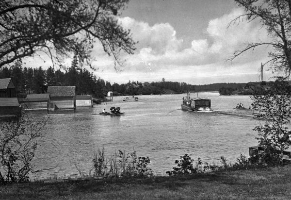 A view of Fish Hook River from shore showing a small group of waterside buildings and small boats on the water.