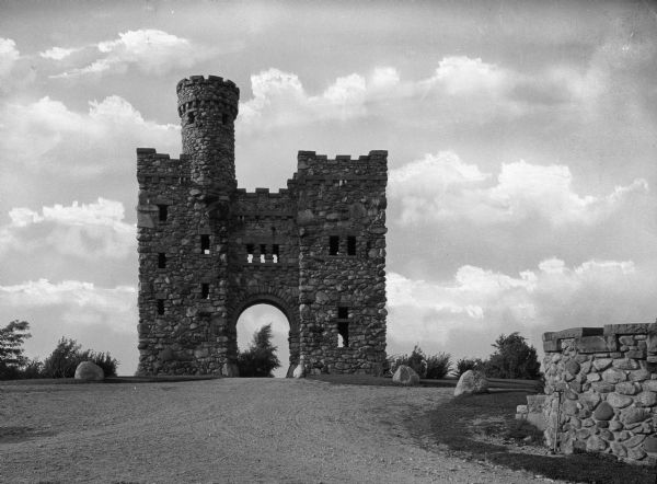 A view of Bancroft Tower, a Romanesque style stone building in open country, from the front drive.