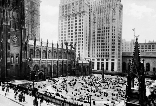 Elevated view of a Gothic revival style Trinity church Wall Street and adjacent cemetery. Modern skyscrapers are in the background.