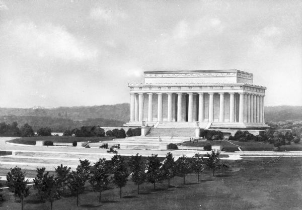 Distant view of the Doric temple style Lincoln Memorial and the National mall including the surrounding manicured park and rolling wooded hills in the background.