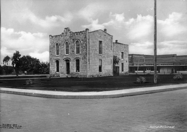 A view of the Spanish Mission style city hall from across the street showing the lawn and other buildings in the background.  Published by Fisher Brothers.